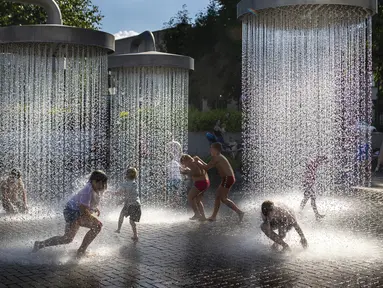 Anak-anak mendinginkan diri di air mancur umum di Vilnius, Lithuania, 26 Juni 2022. Gelombang panas berlanjut di Lithuania saat suhu naik hingga 32 derajat Celcius (89,6 derajat Fahrenheit). (AP Photo/Mindaugas Kulbis)