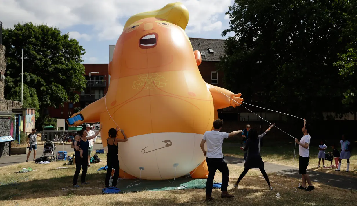 Aktivis mengembangkan balon berbentuk bayi Presiden AS Donald Trump di Bingfield Park, London, 10 Juli 2018. Balon bayi atau disebut Trump Baby itu akan diterbangkan ketika Trump melakukan lawatan perdana ke Inggris pada Kamis (12/7).  (AP /Matt Dunham)