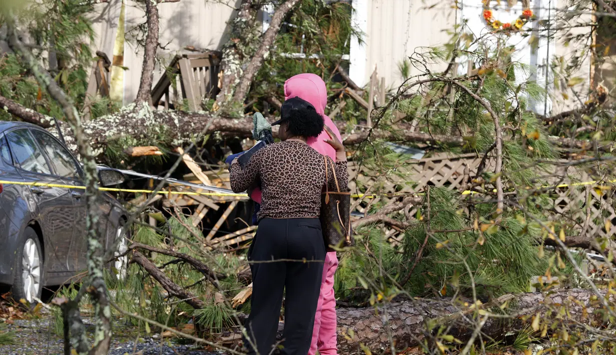 Anggota keluarga saling menghibur di luar rumah mobil yang rusak di Flatwood, Alabama (30/11/2022). Badai Tornado melanda daerah tersebut yang mengakibatkan dua orang tewas di komunitas Flatwood di utara kota Montgomer. (AP Photo/Butch Dill)