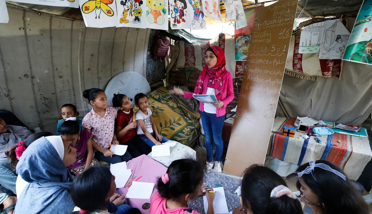 Gadis Palestina, Fajr Hmaid (tengah) mengajar anak-anak dari lingkungannya dalam kelas darurat di Kota Gaza, Kamis (4/6/2020). Gadis berusia 13 tahun tersebut membantu mereka untuk mengejar pelajaran setelah sekolah ditutup oleh pemerintah setempat akibat pandemi Covid-19. (Mohammed ABED / AFP)