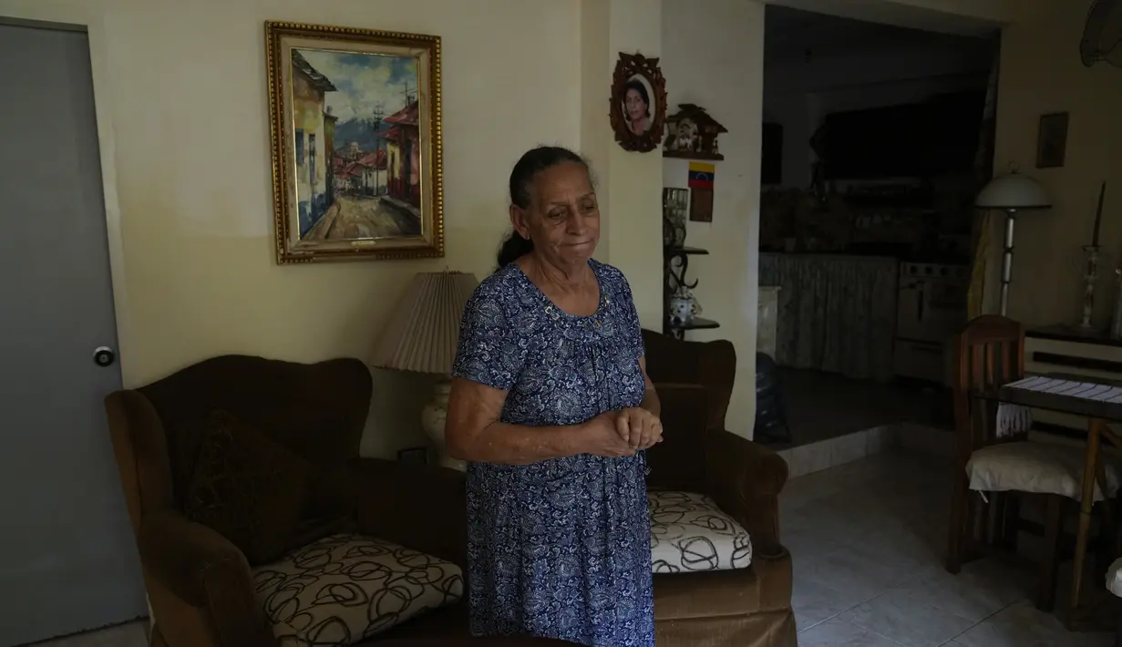 Carmen Castro berdiri di ruang tamu rumahnya, di tengah pandemi virus corona di Caracas, Venezuela, pada 18 Agustus 2021. Castro yang berusia 78 tahun mengatakan sang putri yang berangkat ke Chile tiga tahun lalu mengirimkan uang untuk menambah pensiunnya yang sedikit. (AP Photo/Ariana Cubillos)