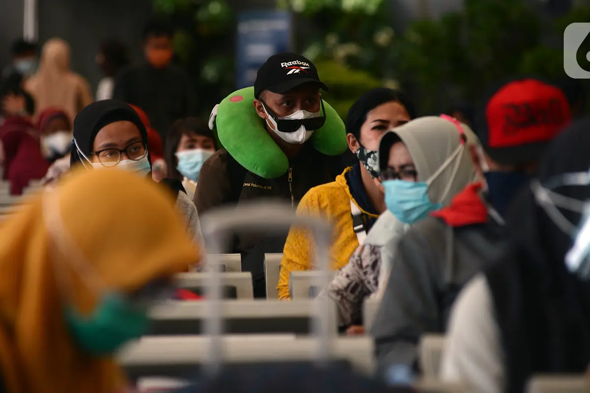FOTO: Petugas KAI Berkostum Natal Bagikan Masker ke Calon Penumpang di Stasiun Senen