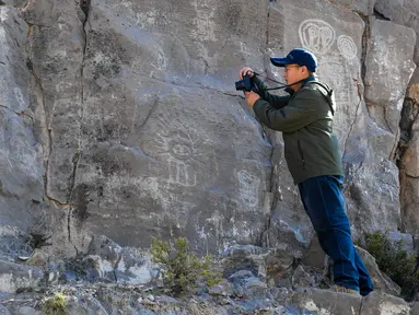 Seorang arkeolog memotret lukisan batu di klaster seni cadas Gunung Zhuozi di Daerah Otonom Mongolia Dalam, China pada 17 Oktober 2020. Gunung Zhuozi adalah tempat dengan banyak lukisan batu yang berguna untuk penelitian tentang asal muasal nomad kuno di China. (Xinhua/Peng Yuan)