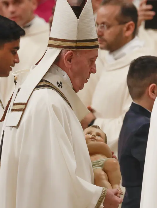Paus Fransiskus membawa  patung bayi Yesus setelah memimpin misa Malam Natal di Basilika Santo Petrus, Vatikan, Selasa (24/12/2019). Paus Fransiskus memberikan khotbahnya seputar makna spiritual dan pribadi mengenai malam saat Yesus dilahirkan di Betlehem. (AP Photo/Alessandra Tarantino)