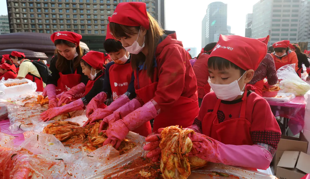 Seorang anak ikut membuat kimchi, hidangan tradisional Korea Selatan, selama Festival Kimchi tahunan di pusat kota Seoul, Jumat (3/11). Acara tersebut dibuat oleh para sukarelawan yang hasilnya didonasikan untuk kaum minoritas. (AP Photo/Ahn Young-joon)