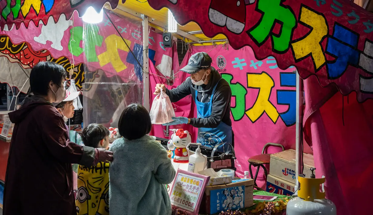 Orang-orang membeli castella pada kios makanan selama pekan raya akhir tahun di Distrik Nihonbashi, Tokyo, Jepang, 26 Desember 2022. Tak hanya menyuguhkan pemandangan indah dan makanan yang lezat, Jepang juga menjadi negara yang tepat untuk merayakan tahun baru. (Yuichi YAMAZAKI/AFP)