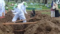 Seorang perempuan mengambil gambar proses pemakaman jenazah korban COVID-19 di TPU Tegal Alur, Jakarta, Kamis (17/12/2020). Hingga hari ini, intensitas pemakamanan korban covid-19 di DKI masih tinggi dengan rata-rata yang dimakamkan mencapai 30 hingga 38 jenazah per hari. (merdeka.com/Arie basuki)