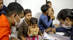 Petugas medis mengumpulkan data dan melakukan pemeriksaan kesehatan terhadap para penumpang kapal feri Putri Yasmin di Pelabuhan Padang Bay, Karangasem, Bali, Rabu, 12 Agustus 2026. (AFP/ Lana Priatna)