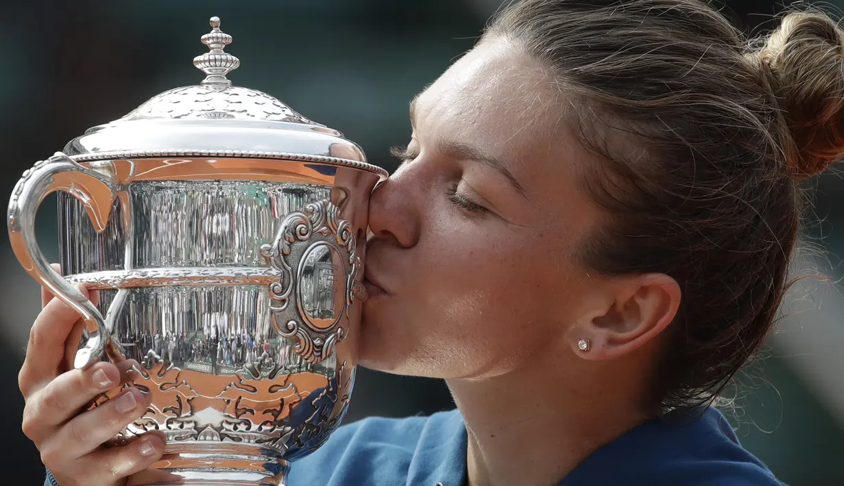 Simona Halep mencium trofi Prancis Terbuka 2018 setelah mengalahkan petenis Amerika, Sloane Stephens di Roland Garros stadium, Paris, Prancis, (9/6/2018). Simona menang 3-6, 6-4, 6-1. (AP/Alessandra Tarantino)