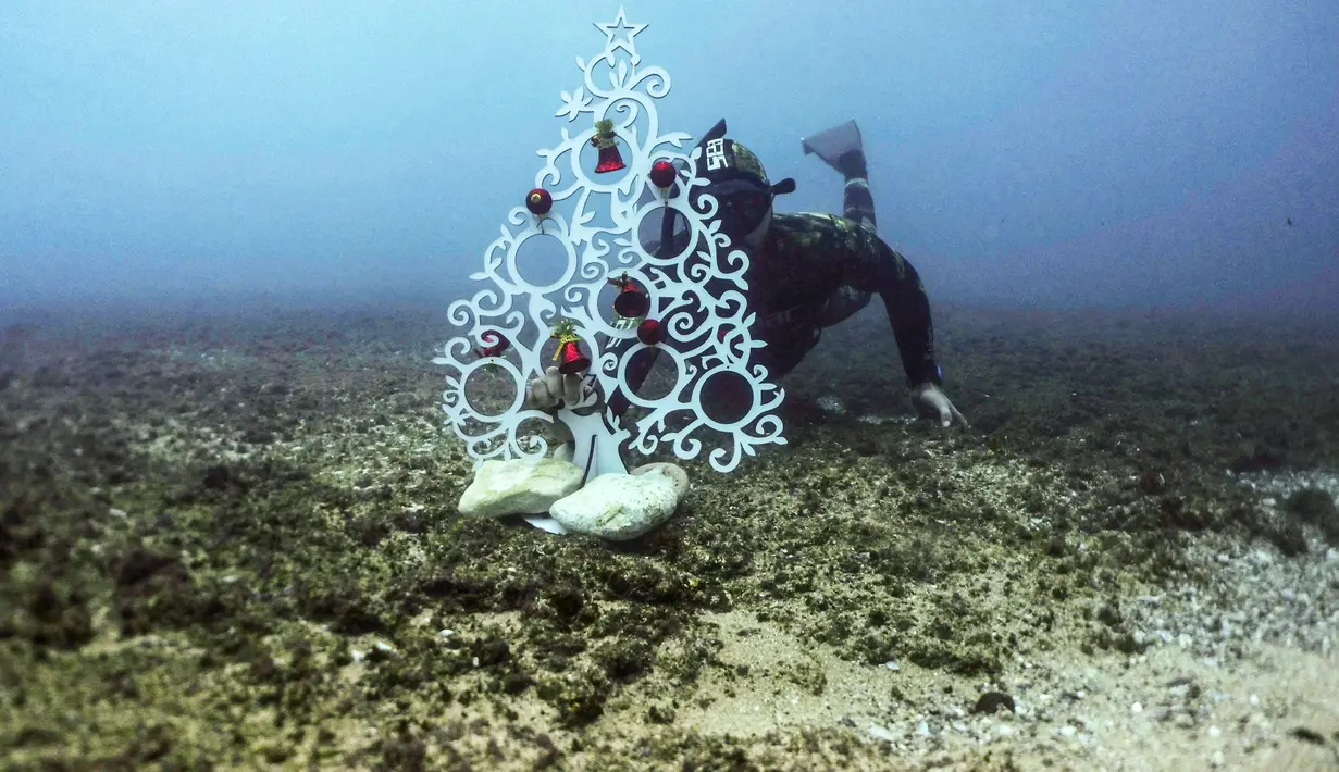 Penyelam menempatkan pohon Natal di dasar laut lepas pantai Tripoli, Lebanon, Selasa (18/12). Hal ini dilakukan untuk menyambut Natal. (IBRAHIM CHALHOUB/AFP)
