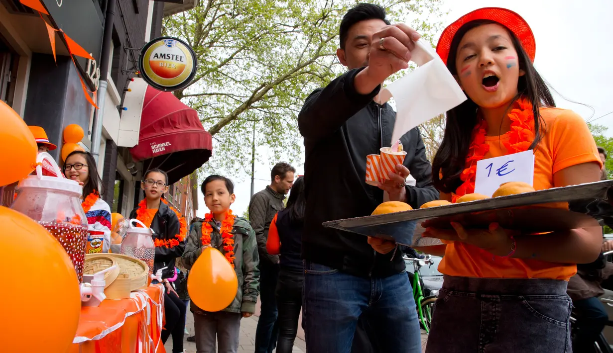 Seorang gadis menjual cupcakes oranye di sebuah stan pada Hari Ulang Tahun Raja atau King's Day di Amsterdam, 27 April 2018. Hari Raja diselenggarakan untuk merayakan hari ulang tahun raja Belanda, Raja Willem Alexander. (AP/Peter Dejong)