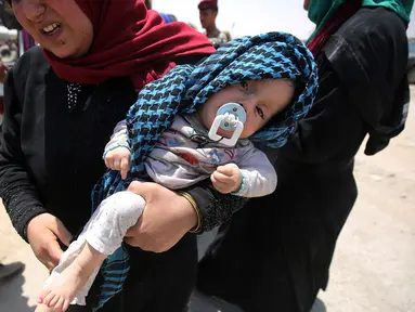 Warga sipil Irak menggendong anaknya saat mengungsi dari Kota Tua di Mosul, 1 Juli 2017. Dana Anak PBB (UNICEF) pada 29 Juni 2017, mengatakan ribuan anak telah terjebak di daerah yang masih dikuasai ISIS di pusat kota tua itu. (AHMAD AL-RUBAYE/AFP)