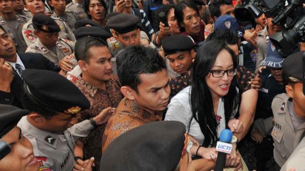 Angelina Sondakh tersenyum saat dikawal petugas keamanan KPK dan polis 