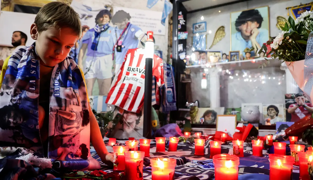 Orang-orang memberi penghormatan saat memperingati mendiang legenda sepak bola Diego Maradona di hari ulang tahunnya di Naples, Italia, 30 Oktober 2022. Legenda sepak bola asal Argentina, Diego Armando Maradona yang lahir pada 30 Oktober 1960 meninggal pada 25 November 2020. (Alessandro Garofalo/LaPresse via AP)