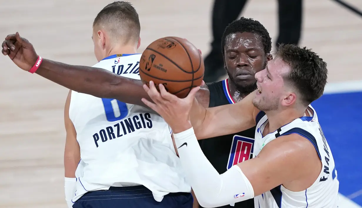 Pebasket Dallas Mavericks, Luka Doncic, berebut bola dengan pemain Los Angeles Clippers, Reggie Jackson, pada gim kedua playoff NBA 2020 di AdventHealth Arena, Kamis (20/8/2020). Maverick menang 127-114 atas LA Clipppers. (AFP/Ashley Landis-Pool/Getty Images)