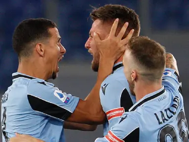 Gelandang Lazio, Sergej Milinkovic-Savic (tengah) berselebrasi dengan rekannya Luiz Felipe dan Manuel Lazzari usai mencetak gol ke gawang Cagliari pada pertandingan lanjutan Liga Serie A Italia di Stadion Olimpiade Roma, di Roma, Italia, Kamis, (23/7/2020). Lazio menang 2-1 atas Cagliari. (AP Photo/