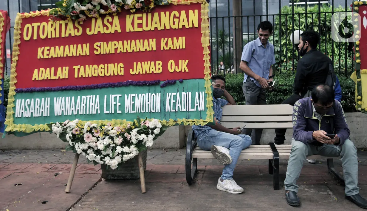 Warga duduk dekat karangan bunga dari korban asuransi Jiwasraya yang terpajang di depan Gedung Pengadilan Tipikor, Jakarta, Rabu (3/6/2020). Puluhan karangan bunga tersebut berisi harapan para korban agar kasus segera tuntas dan uang mereka dapat kembali. (merdeka.com/Iqbal S. Nugroho)
