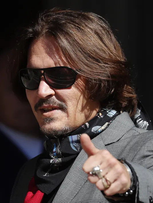 Aktor Johnny Depp memakai kacamata hitam dan syal saat menghadiri sidang pencemaran nama baik di Pengadilan Tinggi, London, Inggris, Selasa (21/7/2020). Johnny Depp menggugat tabloid The Sun atas artikel yang menyebut dirinya telah melakukan kekerasan terhadap sang istri. (AP Photo/Frank Augstein)
