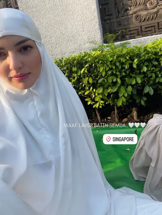 Nia Ramadhani merayakan Iduladha di Singapura, ia pun mengenakan mukena putih polos. Wajahnya dipulas blush on pink serta lipstik tipis. [@ramadhaniabakrie]