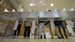 Para pemilih bersiap untuk memberikan suara mereka dalam pemilihan majelis rendah saat perwakilan dari komisi administrasi pemilihan lokal mengamati di sebuah TPS, Tokyo, Jepang, Minggu (31/10/2021). Jepang menggelar Pemilu di tengah pandemi COVID-19. (AP Photo/Eugene Hoshiko)