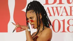 Diana De Brito, yang dikenal sebagai IAMDDB berpose di karpet merah saat tiba menghadiri BRIT Awards 2018 di London, Inggris (21/2). Rapper asal Inggris ini tampil seksi dengan busana transparan sambil membawa mawar berwarna putih. (AFP Photo/Tolga Akmen)