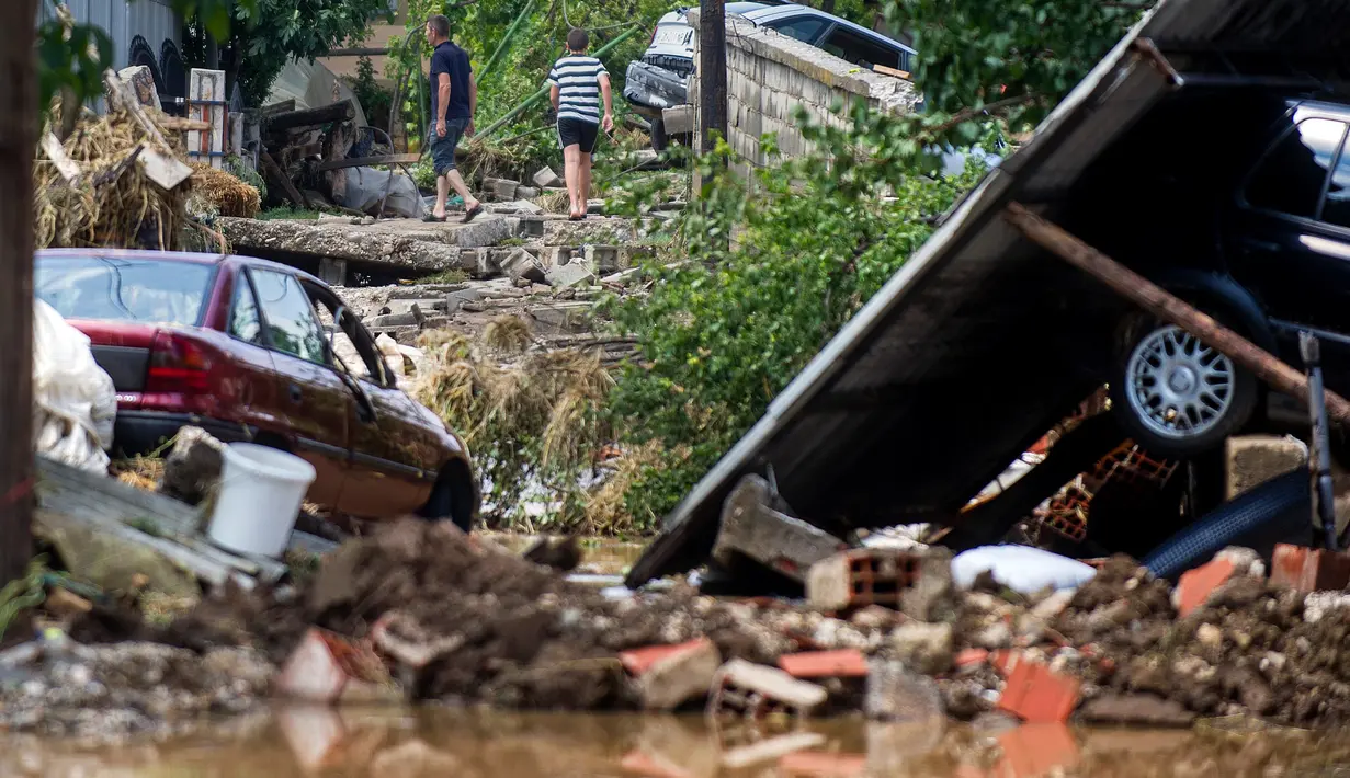 Warga melewati daerah yang rusak akibat banjir bandang di Ibu Kota Skopje, Makedonia, Minggu (7/8). Pemerintah menyatakan keadaan darurat sehari setelah setidaknya 21 orang tewas dalam banjir bandang yang disebabkan badai. (Robert ATANASOVSKI/AFP)