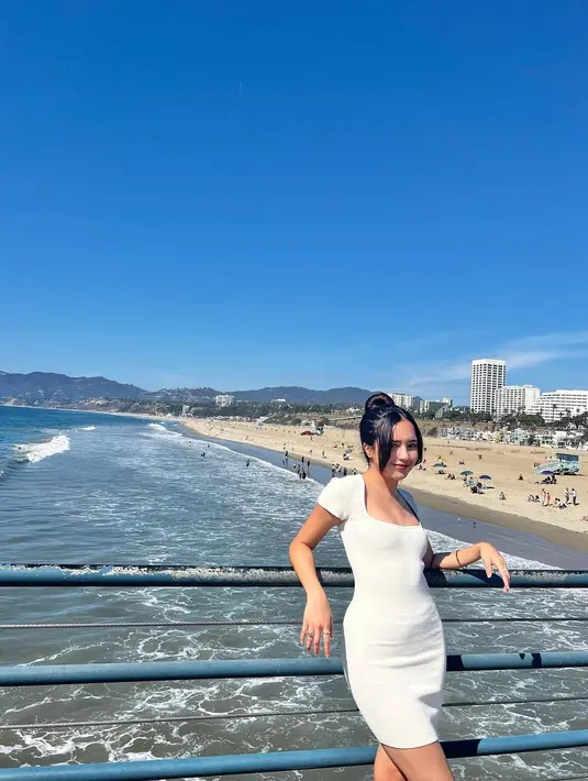 Beby Tsabina berpose dengan latar belakang pantai di California. Beby tampak lebih dewasa memakai mini dress dengan rambut di kuncir. Poni rambutnya 
 yang panjang mempermanis wajahnya yang sudah sempurna. (Instagram/bebytsabina)