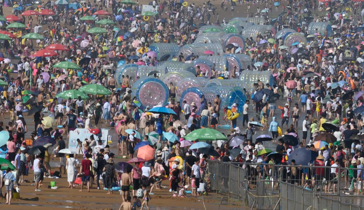 Wisatawan memadati pantai untuk mendinginkan diri di Qingdao, China timur, pada 3 Agustus 2019. Banyak warga di Negeri Tirai Bambu memanfaatkan musim panas dengan mengunjungi pantai untuk mengisi liburan. (Photo by FRED DUFOUR / AFP)
