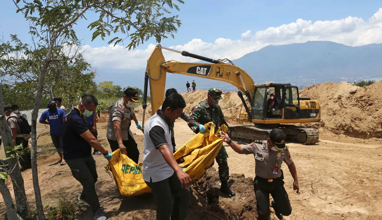 Petugas membawa jenazah korban gempa dan tsunami untuk dimakamkan massal di Palu, Sulawesi Tengah, Senin (1/10). Gempa dan tsunami yang melanda Palu serta Donggala telah menewaskan ratusan korban jiwa. (AP Photo/Tatan Syuflana)