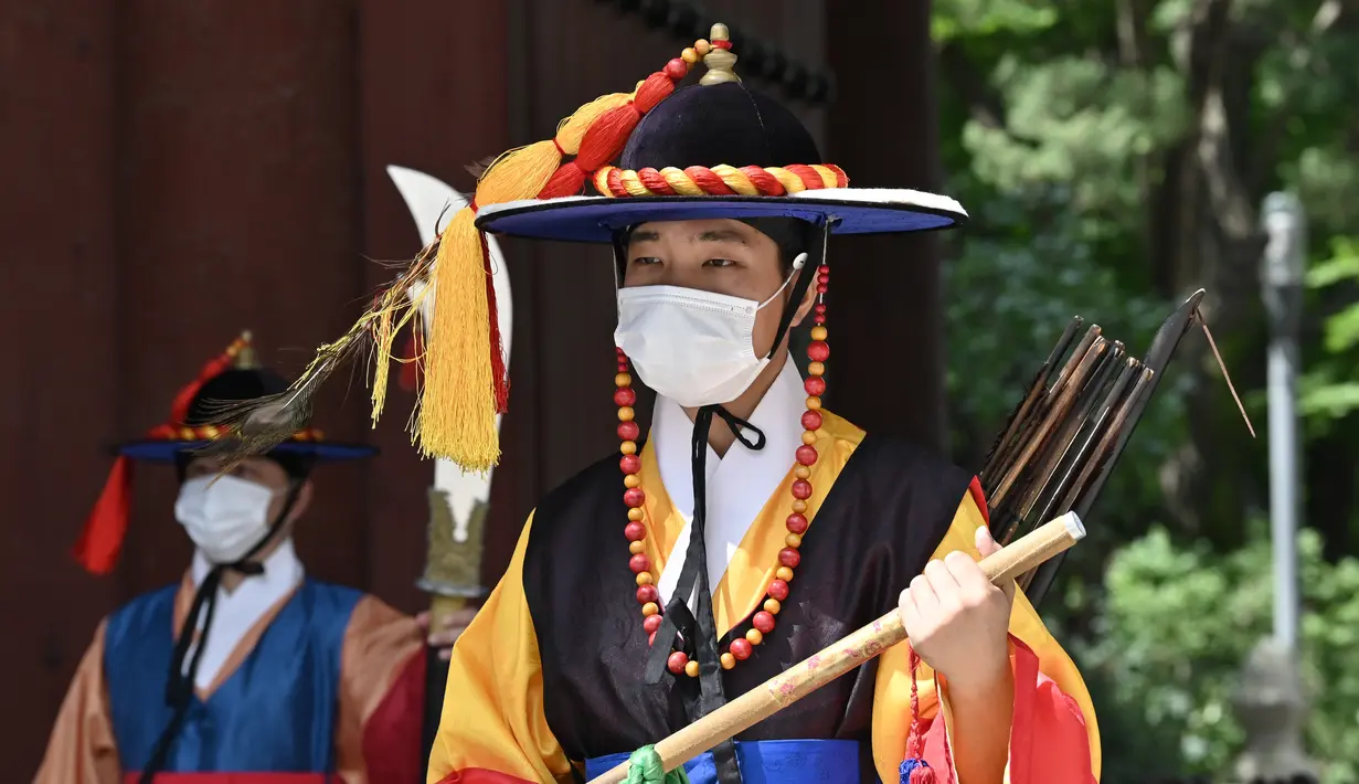 Anggota 'penjaga istana' yang mengenakan masker berdiri untuk turis di gerbang utama Istana Deoksugung di Seoul (4/9/2020). Korea Selatan melaporkan 198 kasus Covid-19 baru pada 4 September, hari ke-22 berturut-turut meningkat tiga digit. (AFP/Jung Yeon-je)