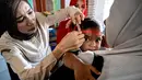 Seorang petugas kesehatan mengukur lingkar kepala bayi dalam program pemeriksaan kesehatan bulanan untuk anak-anak di sebuah pusat layanan terpadu di Banda Aceh, Senin,  10 Agustus 2026. (AFP/ Chaideer Mahyuddin)