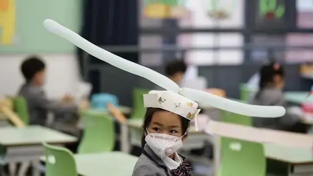 Para murid yang kembali bersekolah di China mengenakan topi yang menjaga jarak mereka antar satu dengan yang lainnya.