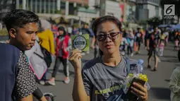 Warga menunjukkan stiker ajakan menggunakan hak pilih pada kegiatan sosialisasi pemilu di kawasan Bundaran HI, Jakarta, Minggu (14/4). Sejumlah Komunitas mensosialisasikan kegiatan pemilu damai tanpa hoaks dan golput menjelang pelaksanaan pemilu 17 April 2019 mendatang. (Liputan6.com/Faizal Fanani)