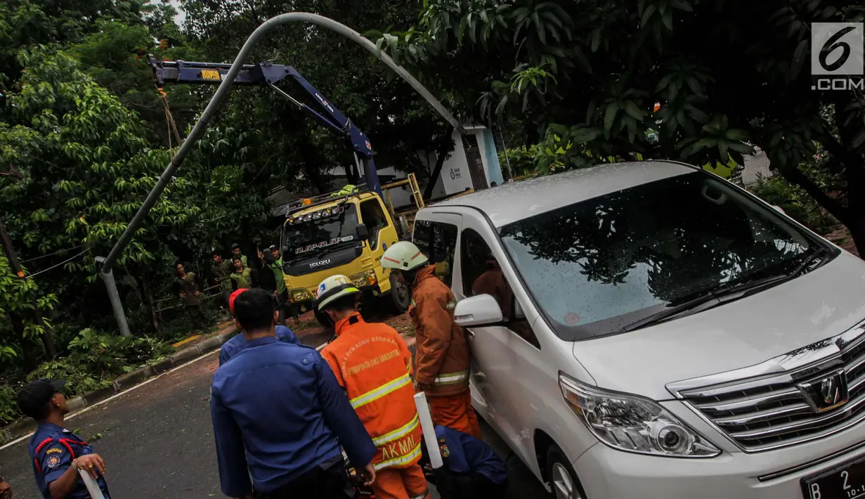 Sebuah mobil tertimpah lampu jalanan di kawasan jalan purworejo Menteng, Jakarta, Senin (27/11). Akibat hujan deras dan angin kencang sebuah pohon tumbang dan lampu jalan mengenai mobil Alphard putih yang terparkir. (Liputan6.com/Faizal Fanani)