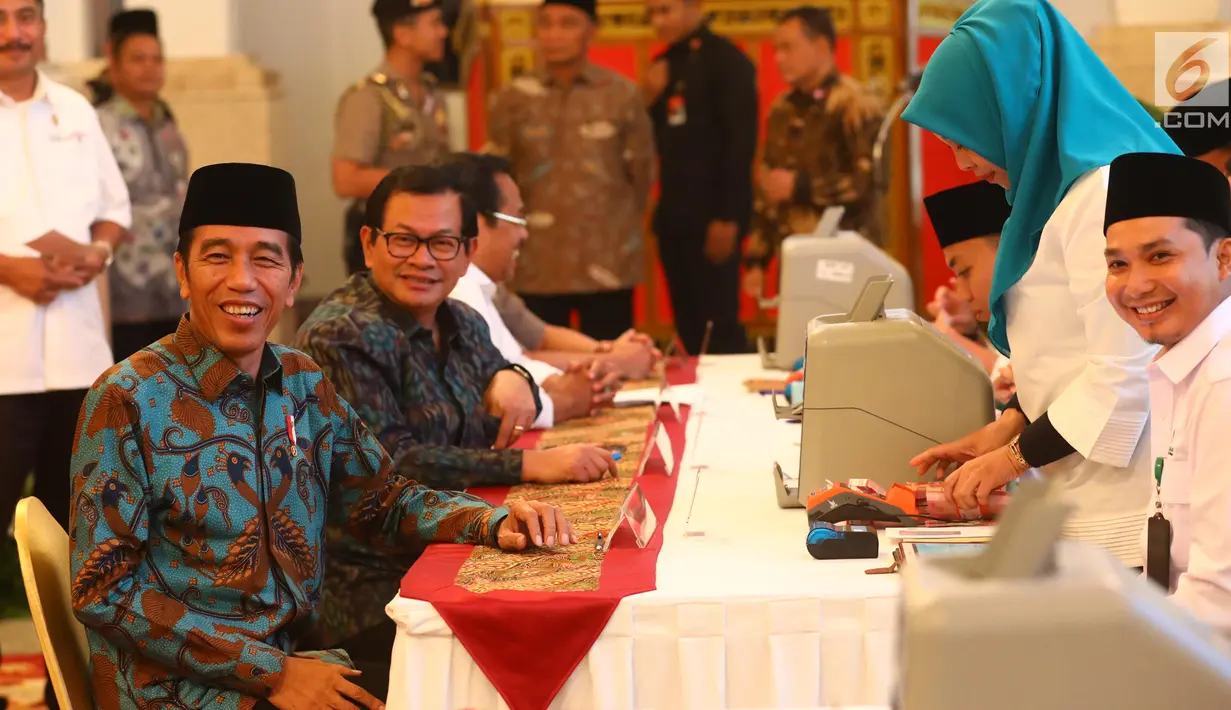 Presiden Joko Widodo (kiri) dan Sekretaris Kabinet Pramono Anung ketika menyerahkan zakat mal di Istana Negara, Jakarta, Kamis (16/5/2019). Jokowi bersama para menteri, kepala lembaga, hingga direksi BUMN melakukan pembayaran zakat mal melalui Baznas. (Liputan6.com/Angga Yuniar)