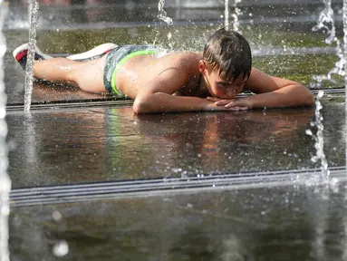 Seorang anak laki-laki menikmati cuaca panas sambil beristirahat di air mancur sebuah taman di sebelah tanggul Sungai Moskow, di Moskow, Rusia, Rabu (14/7/2021). Cuaca panas di Moskow berlanjut dengan suhu mencapai 34 derajat Celcius (93,2 Fahrenheit) dalam sehari. (AP Photo/Pavel Golovkin)