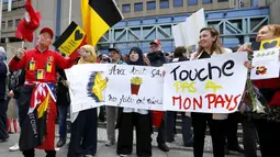 Warga membawa poster saat aksi pawai menentang teror dan kebencian di Brussels, ibu kota Belgia, Minggu (17/4). Aksi yang berlangsung dengan tenang dan ‘tanpa suara’ ini untuk menunjukkan persatuan usai serangan teroris di Brussels. (REUTERS/Yves Herman)