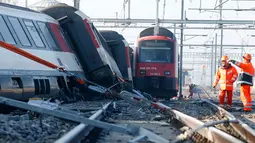 Petugas berdiri di samping kereta melihat kondisi dua kereta yang bertabrakan di Zurich, Swiss, (20/2/2015). Kereta bertabrakan di Swiss yang menyebabkan beberapa orang terluka dan rute komuter tergangu. (Reuters/ Arnd Wiegmann)