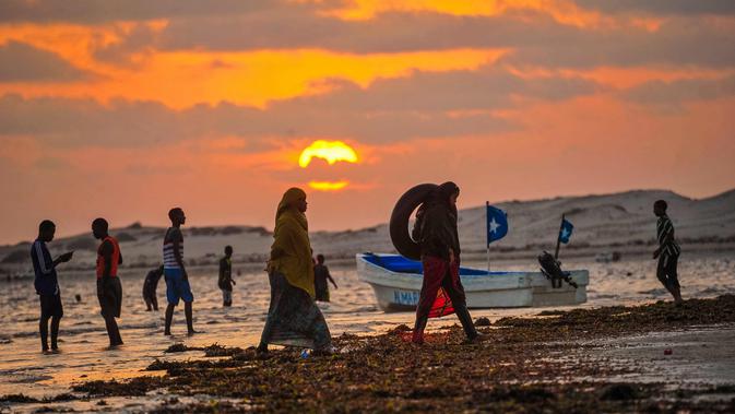 Sejumlah warga berkumpul saat matahari terbenam di Pantai Jazera di pinggiran Mogadishu, Somalia (24/11). Pantai ini jadi tempat rekreasi populer bagi warga Somalia. (AFP Photo/Mohamed Abdiwahab)