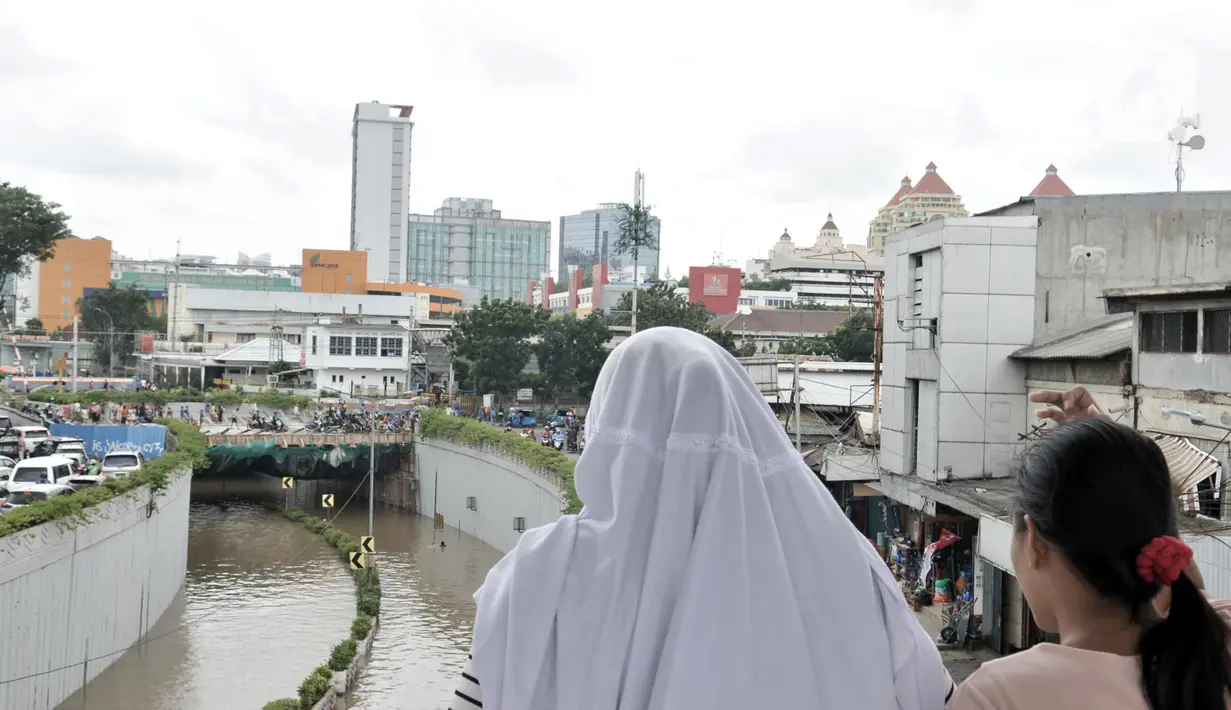 Warga melihat banjir yang merendam Underpass Senen, Jakarta, Selasa (25/2/2020). Hujan deras yang mengguyur Ibu Kota sejak dini hari tadi menyebabkan Underpass Senen terendam banjir setinggi dua meter sehingga mengakibatkan akses Cempaka Putih-Pasar Senen terputus. (merdeka.com/Iqbal Nugroho)