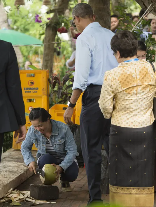 Barack Obama menunggu kelapa yang sedang di buka di sepanjang Sungai Mekong di Luang Prabang, Laos (7/9). Obama menjadi presiden AS pertama yang mengunjungi Laos dan mendarat di Vientiane akhir pada 5 September. (AFP PHOTO/SAUL Loeb)