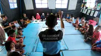 Seorang tim dukungan Psikososial bermain bersama anak-anak korban gempa tsunami Palu di halaman kantor Dinas Sosial Palu, Sulawesi Tengah, Sabtu (6/10). Trauma healing dilakukan agar anak-anak kembali ceria. (Liputan6.com/Fery Pradolo)
