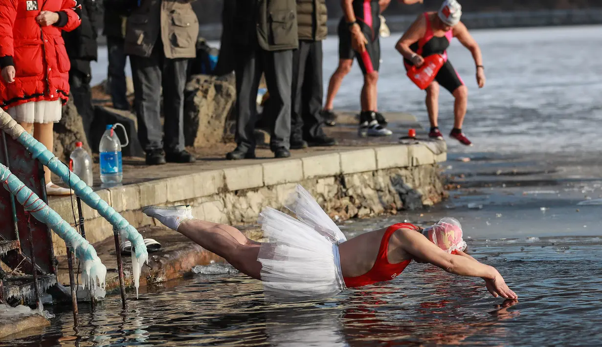 Seorang wanita melompat untuk berenang di danau  yang sebagaian beku dengan es saat suhu minus 20 derajat Celcius di Shenyang di provinsi Liaoning timur laut China (10/12). (AFP Photo/Str/China Out)
