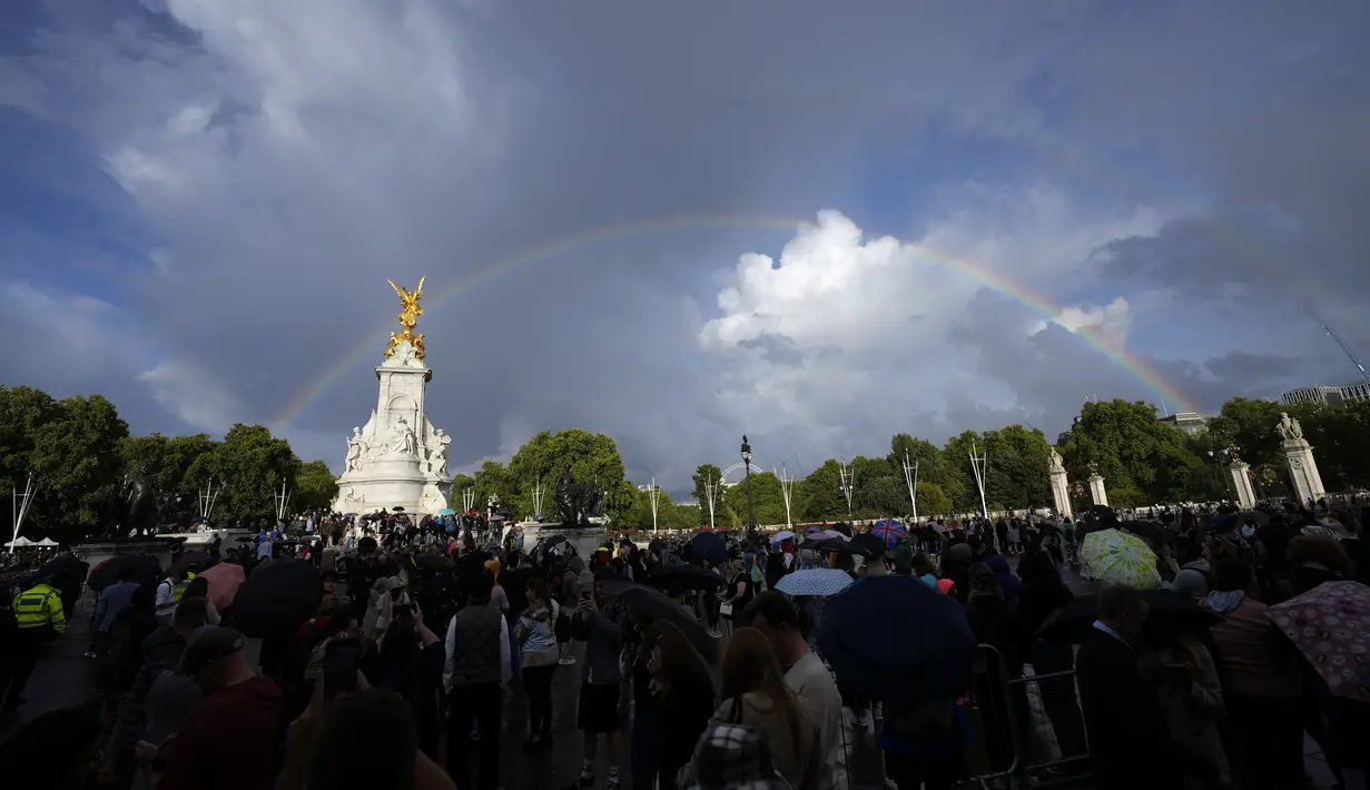 Orang-orang berkumpul di luar Istana Buckingham saat pelangi ganda muncul di atas langit London, Kamis, 8 September 2022. Dikutip dari People, pelangi tersebut muncul sesaat sebelum kematian Sang Ratu diumumkan ke penjuru negeri. Fenomena ini pun mencuri perhatian publik. (AP Photo/Frank Augstein)