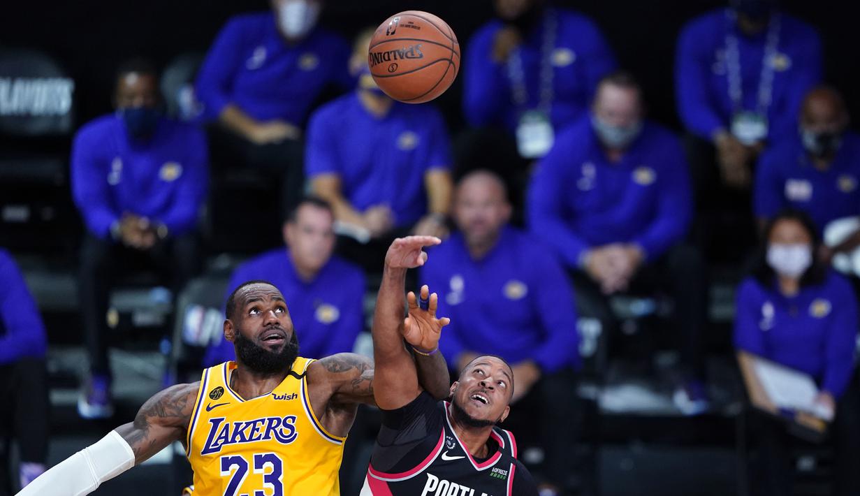 Pebasket Los Angeles Lakers, LeBron James, berebut bola dengan pebasket Portland Trailblazers, CJ McCollum, pada babak pertama playoff NBA 2020 di AdventHealth Arena, Rabu (19/8/2020). LA Lakers takluk 93-100 atas Portland Trailblazers. (AFP/Ashley Landis-Pool/Getty Images)