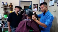 Abah Atrox tengah memberikan bimbingan cukur rambut kepada siswa didiknya di Desa Banyuresmi, Kabupaten Garut, Jawa Barat. (Liputan6.com/Jayadi Supriadin)