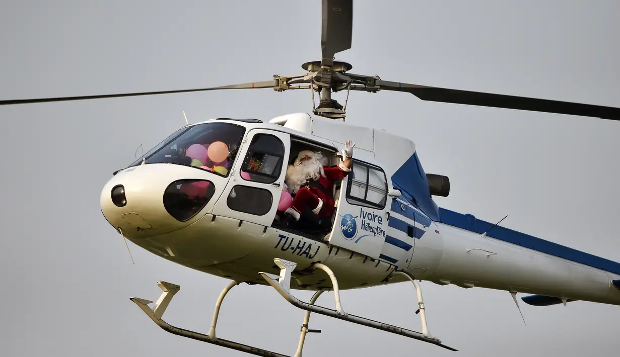 Seorang pria mengenakan kostum Santa Claus melambaikan tangan saat tiba di istana kepresidenan di Pantai Gading (23/12). (AFP Photo/Sia Kambou)