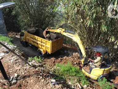 Petugas menggunakan alat berat backhoe membersihan jalan dari longsoran tanah di RT 04/RW 03, Kademangan, Keranggan, Setu, Tangerang Selatan, Banten, Selasa (3/12/2019). Longsor pada Senin sore kemarin menewaskan seorang pengendara sepeda motor yang melintas, Anggi (23). (merdeka.com/Arie Basuki)