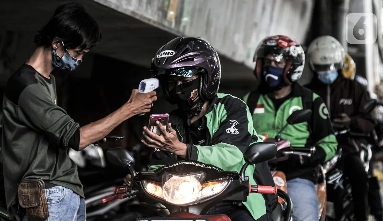 Petugas mengecek suhu tubuh pengojek daring saat pemeriksaan rutin di Posko Aman Covid-19, Jalan Ahmad Yani, Jakarta, Selasa (11/8/2020). Posko Aman Covid-19 rutin digelar untuk memeriksa kesehatan ojol guna mencegah penyebaran corona selama beroperasi di masa pandemi. (merdeka.com/Iqbal Nugroho)