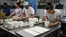 Andrea Schulz dan rekannya menyiapkan kue berbentuk tisu toilet di toko roti Schuerener Backparadies di Jerman, 26 Maret 2020. Kelangkaan kertas tisu toilet memunculkan ide bagi pemilik toko roti, Tim Kortuem, membuat kue menyerupai barang yang diburu warga di tengah Covid-19. (Ina FASSBENDER/AFP)